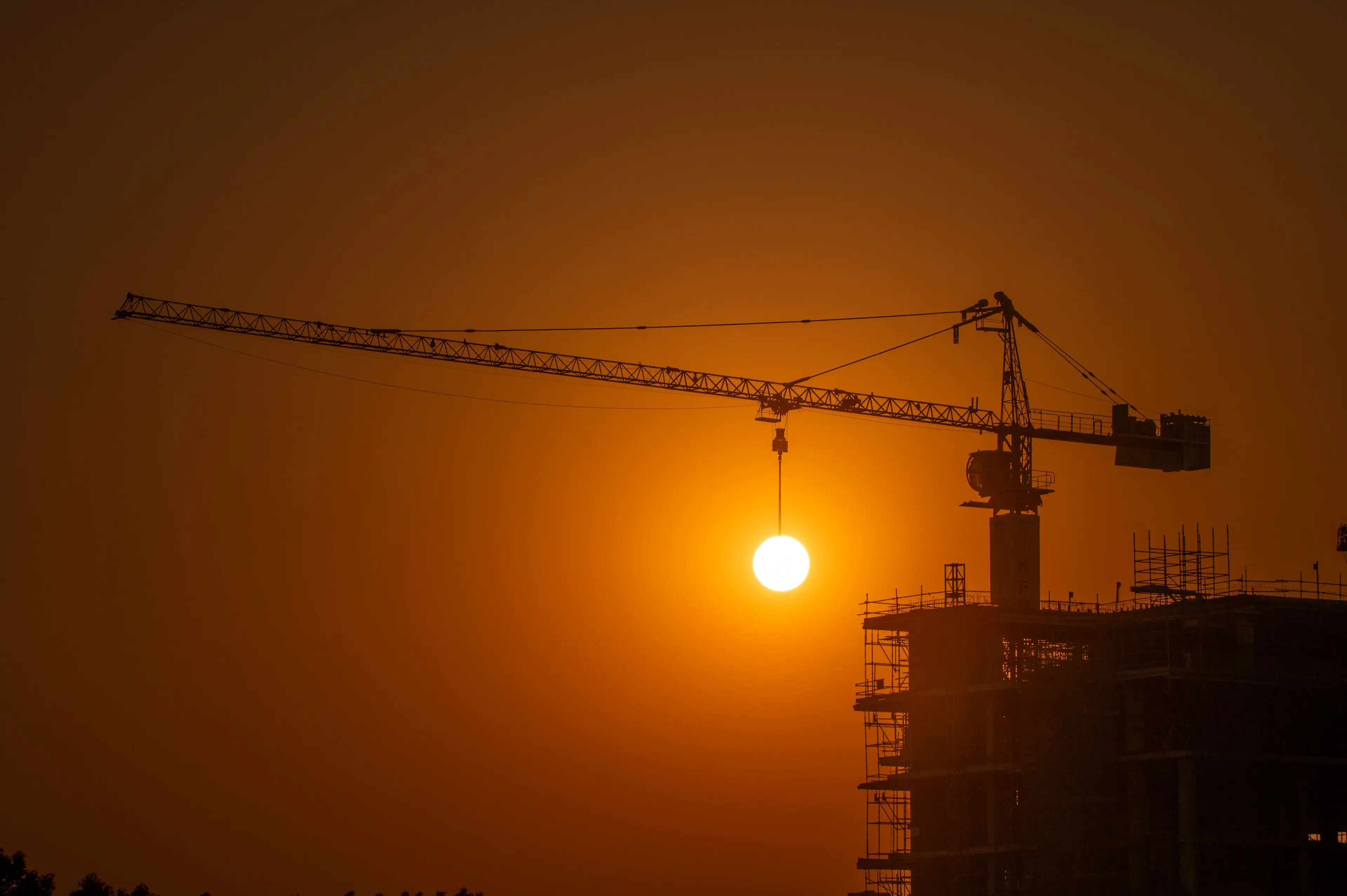 Construction workers silhouetted against the sun on an infrastructure project
