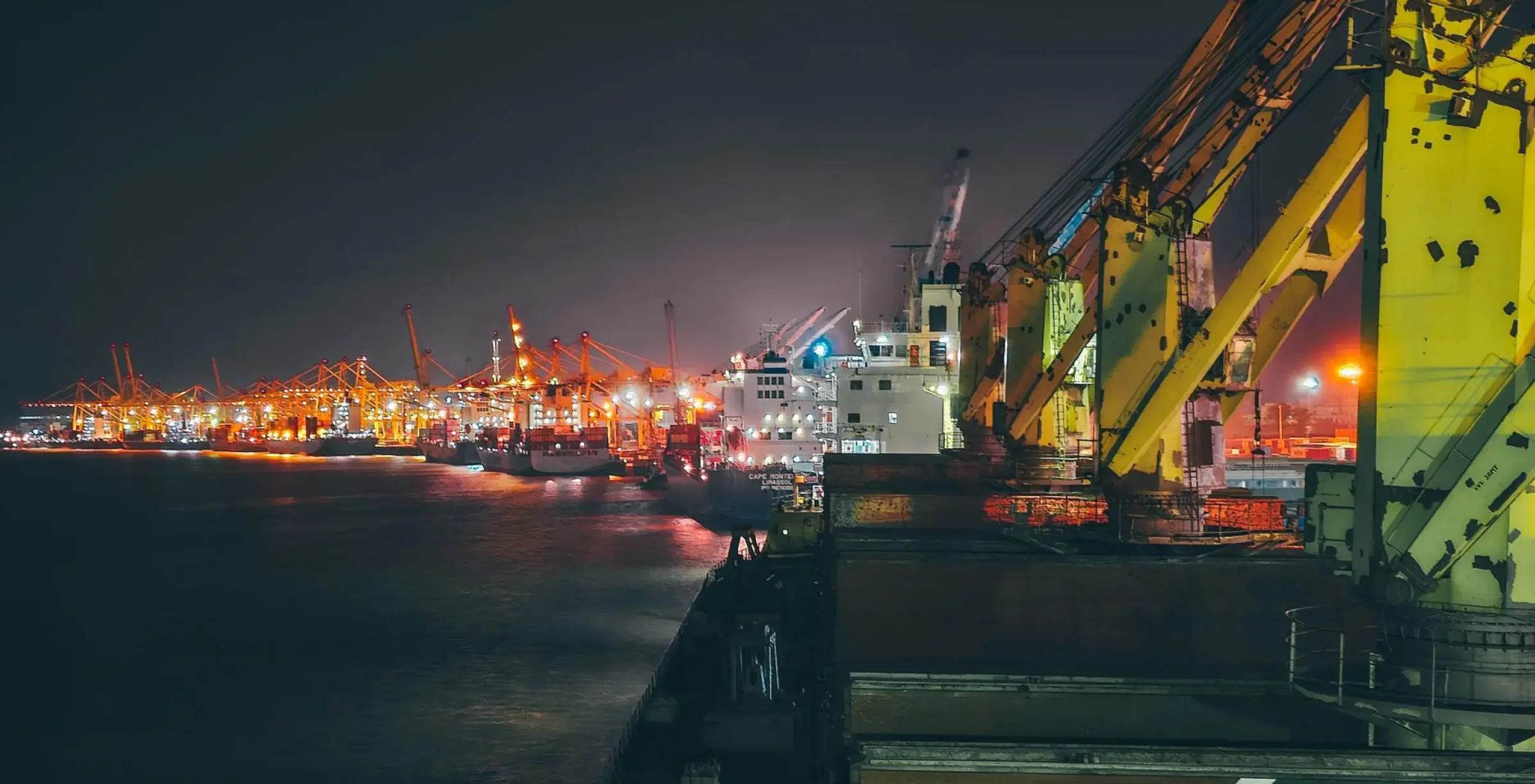 Nigerian port at night with container cranes and cargo vessels along the quay