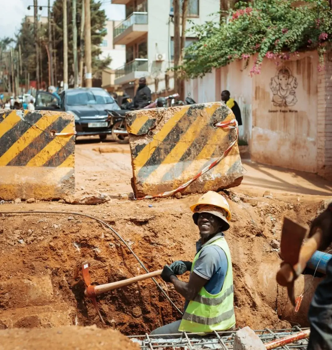 Civil works crew excavating a trench beside road barriers