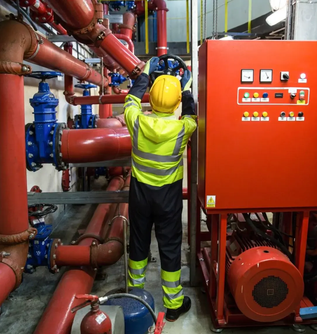 Technician in PPE operating valves in a fire-pump plant room
